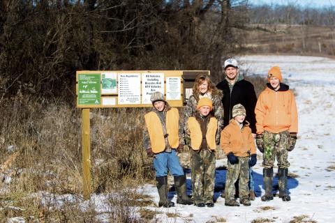 Family posing in front of an MRAP sign.