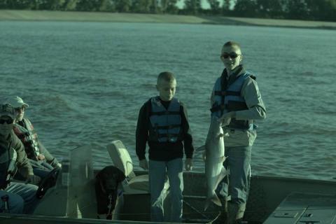 2 boys on a boat with a blue catfish