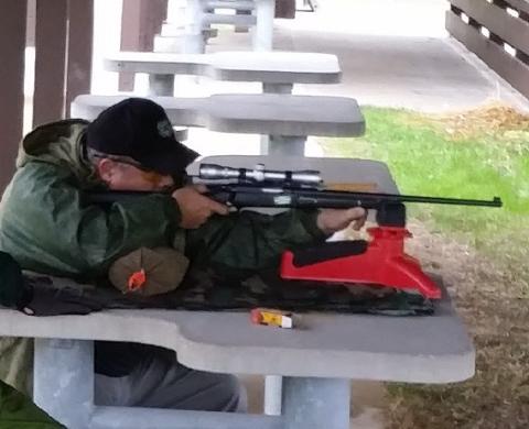 A man sights in a rifle at an MDC shooting range.