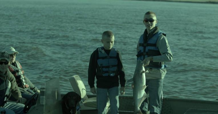 2 boys on a boat with a blue catfish